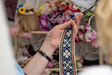 Women is looking at handmade weaved belt.  Ornamental Latvian belt - National symbols of Latvia.