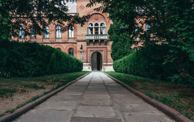 Fototapeta na wymiar Alley of the old garden and the building of the Metropolitan Residence in Chernivtsi, Ukraine