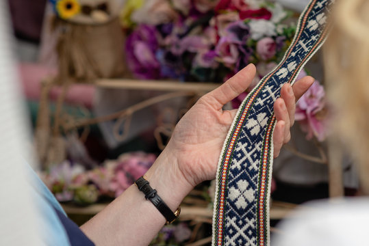 Women is looking at handmade weaved belt.  Ornamental Latvian belt - National symbols of Latvia.