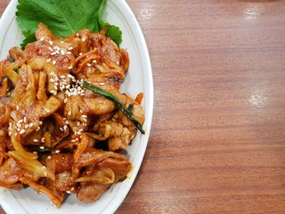 Korean food style, Top view of spicy stir fried pork  on white plate, Space for text in template, Jeyuk bokkeum is korea traditional on wooden table