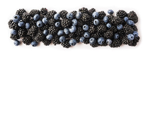 Ripe blackberries and blueberries isolated on white background. Black and blue berries on a white. Berries at border of image with copy space for text. Top view.