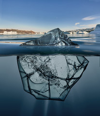 block of ice with underwater view and greenland background.