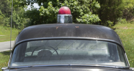 Obraz premium Vintage 1950s Sheriff's patrol car parked on grassy knoll.