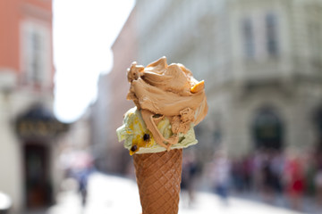 melting delicious ice cream in waffle cone gelato pistachio salty caramel holding female hand
