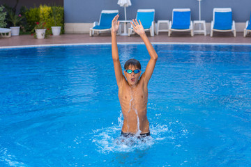 Boy, teenager, athlet having fun jumping in swimming pool.