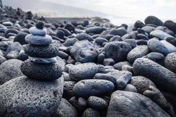 Fototapeta na wymiar Pile of black lava stones at coastline at Puerto de la Cruz, Tenerife, Canary Islands, Spain