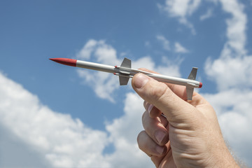 the person's hand holds a rocket aimed at the sky. missile Warhead, weapons of mass destruction,...
