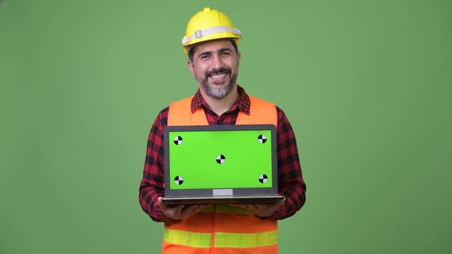 Handsome Persian bearded man construction worker showing laptop