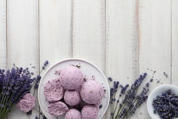 Natural cosmetics. Handmade lavender bath bombs, lavender flowers and towel on white wooden planks, top view