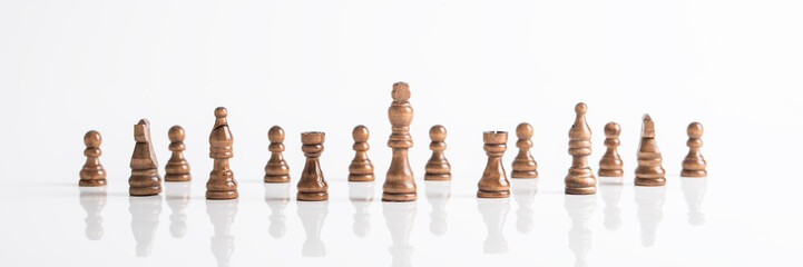 Wide panorama image of dark chess pieces on white table