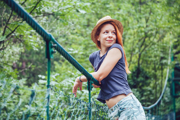 Young woman in the forest on the wooden bridge enjoying summer