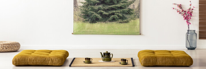 Kettle and cups on tatami mat between cushions in dining room interior in a japanese design. Real...