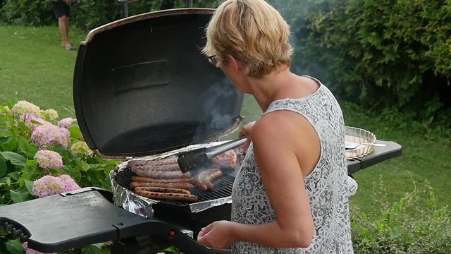  woman cooks the meat on the barbecue