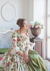 Beautiful woman in long medieval dress sitting near window