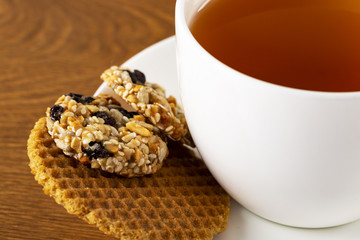Tea in a white cup and cookies on a wooden background. Macro. Copy space.