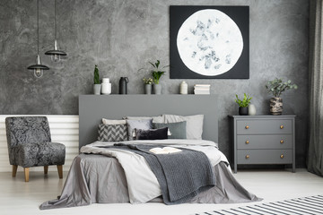 Moon art decor on the wall in a stylish grey bedroom interior with a big bed in the middle and an...
