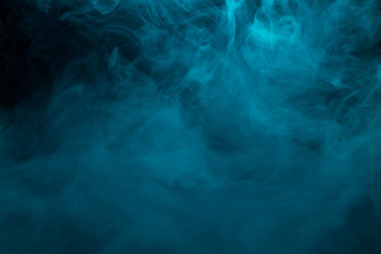 Colored turquoise smoke on a black background closeup