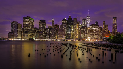 Fototapeta premium New York Skyline at night from Brooklyn with pillars arches in the foreground