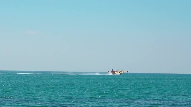 A firefighting aircraft in an emergency situation, skimming water from the sea in Spain.
