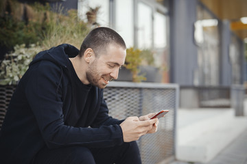 Bearded man looking at mobile phone screen and smiling.
