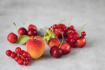 Summer bright berries and fruits on a gray concrete background. The concept of raw food, vegetarianism, healthy eating.