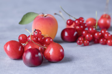 Summer bright berries and fruits on a gray concrete background. The concept of raw food, vegetarianism, healthy eating.