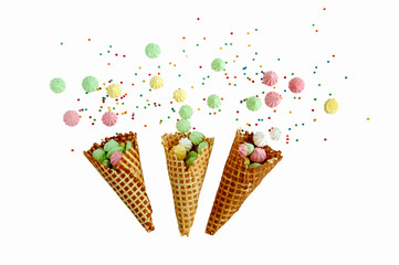 three waffle cone with colorful meringues on white background