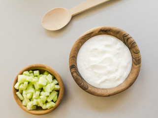 Sliced cucumber and sour cream in wooden bowls