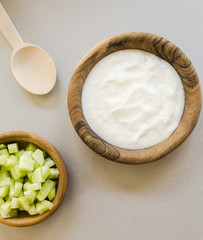 Sliced cucumber and sour cream in wooden bowls