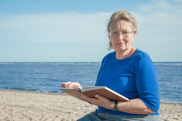 elderly woman with a book on the sea background