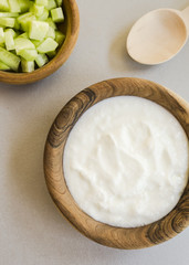 Sliced cucumber and sour cream in wooden bowls
