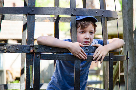 Boy in cage, medieval penalty device, a tourist attraction in an old castle. Vacations and sightseeing. Poland.