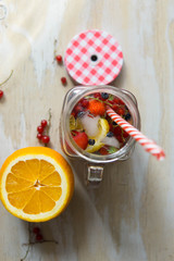 Lemonade with red berries, red cherry, strawberry, blueberry and orange, with ice cubes, close-up and isolated