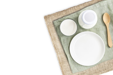 A bottle of milk and glass of milk with blank dish and wooden spoon on green cloth and sackcloth isolated on white background for food and healthy concept. with copy space for text.