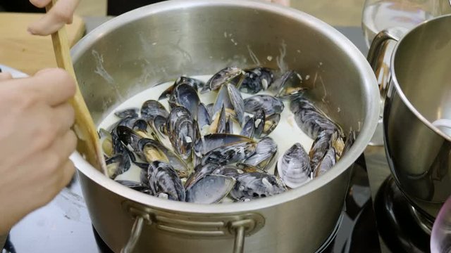 Close-up shot of mussels are being stewed in a saucepan on an electric stove. 4K