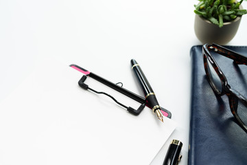 pen and clipboard with blank sheet, glasses on diary book on white background with copy space