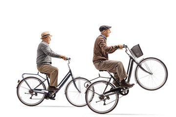 Seniors riding bicycles with one of them doing a wheelie
