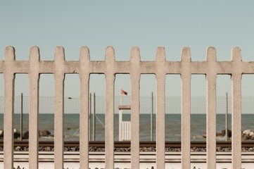 Baywatch tower with red flag behind the railway (Pesaro, Italy)