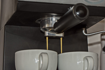 an espresso machine and two white cups