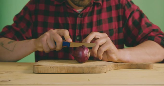 Young man cutting onion in slow motion on green screen