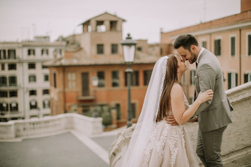 Young newly married couple  posing in Rome with beautiful and ancient architecture in the background