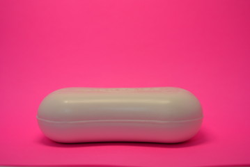 On a bright colorful pink paper background is located and placed a cosmetic antibacterial white soap for face and skin