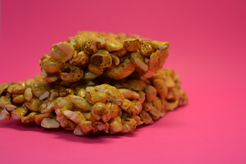 On a bright colorful pink paper background is located and placed from a delicious and sweet grilling of air corn kernels, popcorn with caramel