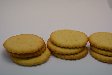 On a white paper background, fresh biscuits are placed and placed, crispy delicious round crackers with dots