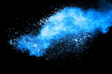 Abstract blue dust explosion on black background. Freeze motion of blue powder splash. Painted Holi...