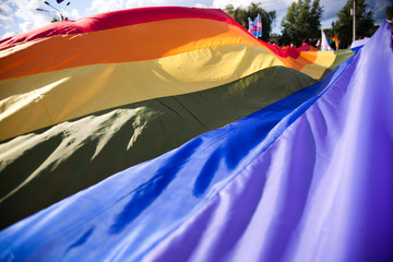 people holding giant rainbow flag at pride parade - LGBT symbol