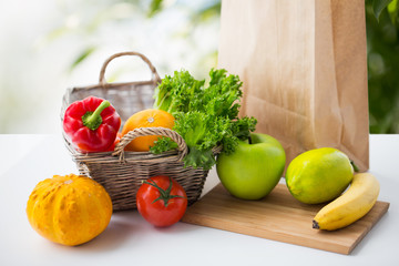 diet, vegetarian food and healthy eating concept - basket with fresh ripe juicy vegetables, greens and fruits on table over green natural background