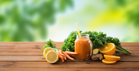 healthy eating, food, dieting and vegetarian concept - glass jug of carrot juice, fruits and vegetables on wooden table over green natural background