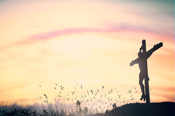 Silhouette of Jesus with Cross over sunset background.