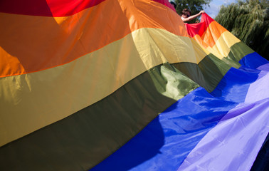 people holding giant rainbow flag at pride parade - LGBT symbol